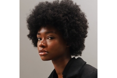 A Black woman looking into  the camera with a blank expression.